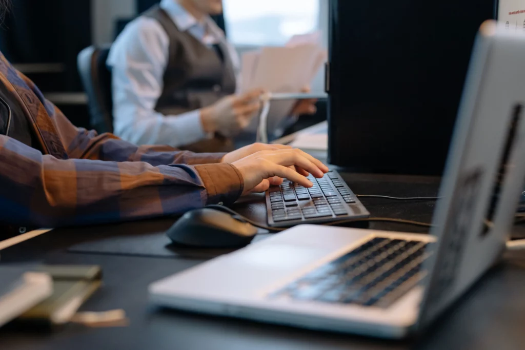 Two people working at a desk with computers